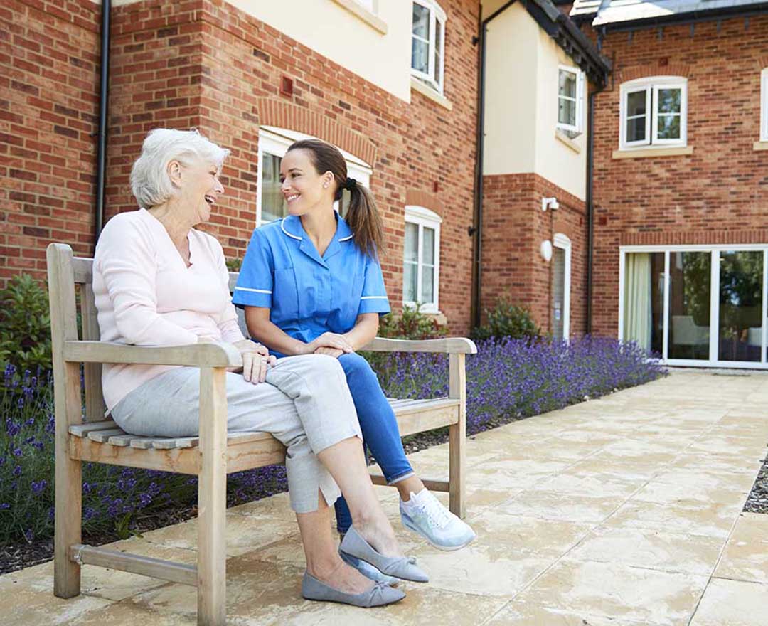 A caregiver smiling while supporting a client during an in-home visit